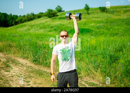 Man pushing dumbbell in hand over head Stock Photo