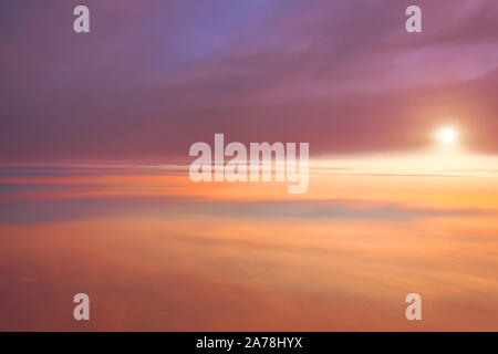 Amazing view from plane between different layers of clouds on the sky, sunrise sun Stock Photo