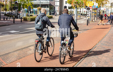 Eindhoven Netherlands, October 10, 2019. Rear view of people riding bikes, urban background, sunny autumn day Stock Photo