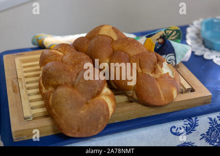 Jewish challah bread lying on a wooden board and tablecloth before Shabbat Stock Photo