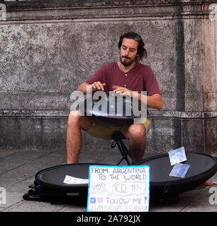 Single male busker playing an unusual upturned steel lid with dents like a  steel drum. Sitting on a stool on a Venetian street for the tourists Stock Photo
