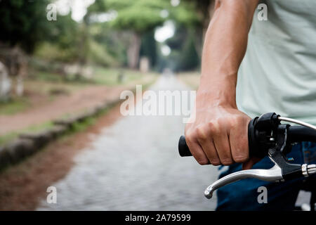 closeup of a young caucasian man riding a bike by the Via Appia Antica road in Rome, Italy Stock Photo