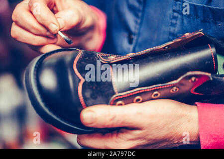 Hands of an experienced worker putting paint on the parts of the shoe. Stock Photo