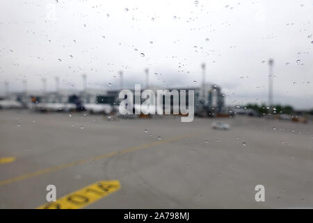 Munich international airport unfocused view from plane window with water drops on the glass in rainy weather Stock Photo