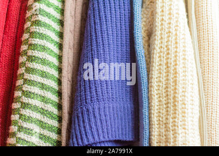 warm knitted things, sweaters and dresses hang on hangers Stock Photo