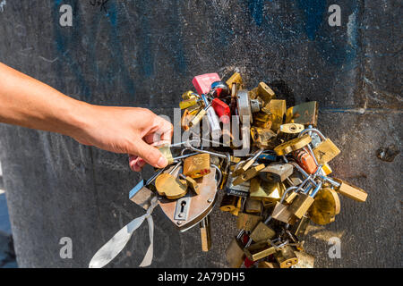 A hand is holding the padlocks on the wall of riverbank of Seine River, Paris, France. Stock Photo