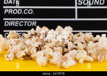 Popcorn and clapperboard on colorful background. Stock Photo