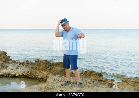 young man in hat and shorts posing on the seashore Stock Photo