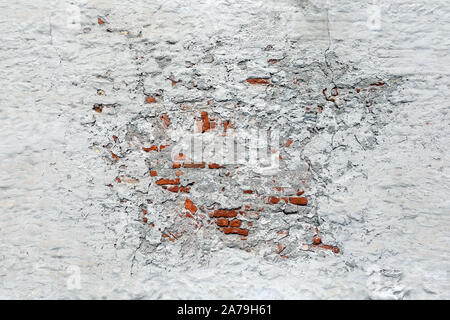 Old vintage red brick wall covered with white plaster damaged in centre as conceptual background front view horizontal Stock Photo