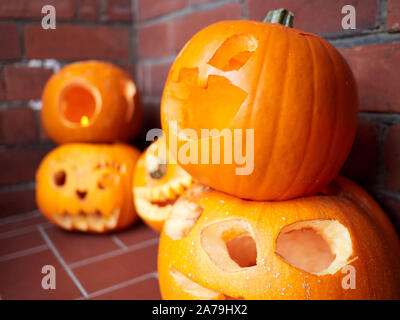 Five pumpkins carved for Halloween on a front door step in England ready for Trick or Treat door knockers Stock Photo