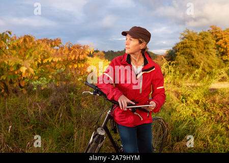 Middle age female cyclist checks weather forecast on a tablet pc Stock Photo