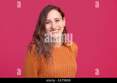 Portrait of cheerful young woman smiling and looking confident at the camera over pinky background Stock Photo