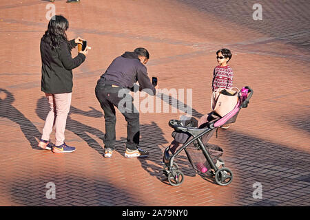 An Asian family taking photographs of themselves in Pioneer Courthouse Square in downtown Portland, Oregon Stock Photo