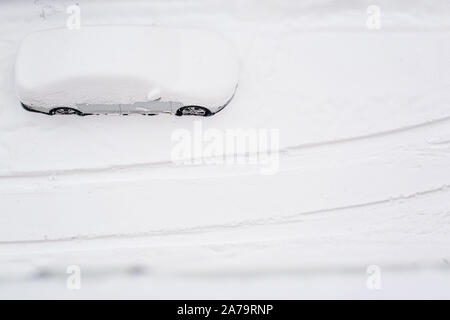 Top view on silver car burried in snow on the road after blizzard. Heavy snow in the city. After snow storm. Copy space. Snow storm. Space for text. Stock Photo