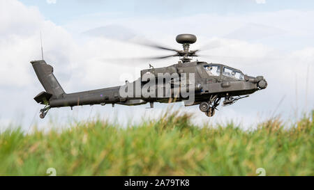 A British Army Apache attack helicopter of the Army Air Corps prowling around Salisbury Plain Training Area at low level during a training exercise. Stock Photo