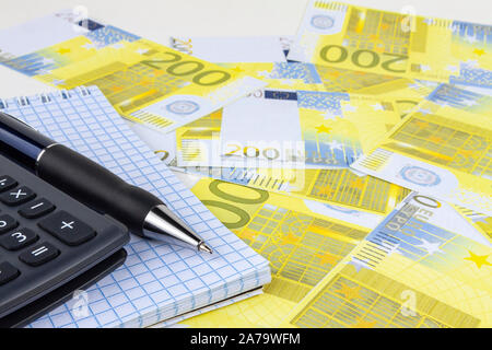 Automatic pen, calculator, notebook on a background of money close-up. Stock Photo