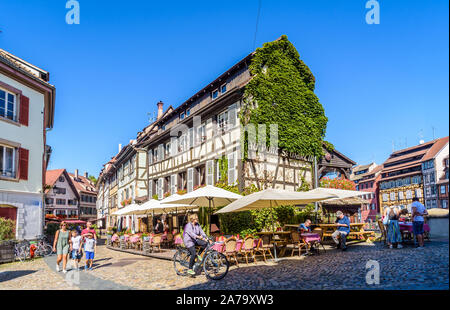 Tourists strolling in front of the restaurant 'Au Pont Saint-Martin' set in a half-timbered house in the Petite France quarter in Strasbourg, France.