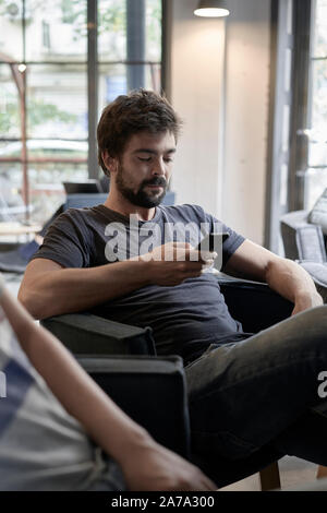 Handsome young businessman is resting in cafe. Attractive bearded man is sitting at the table in cafeteria Stock Photo