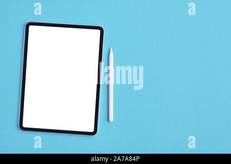 Tablet mockup with white pencil on blue background. Top view. Copy space. Stock Photo