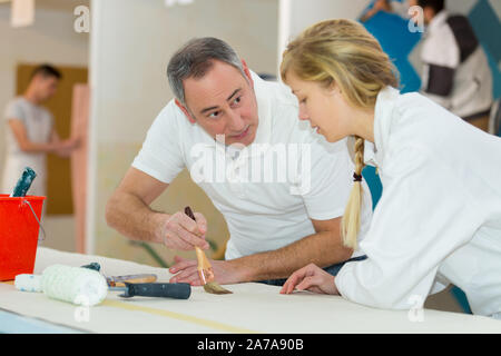 painter teaching paintbrush technique to apprentice Stock Photo