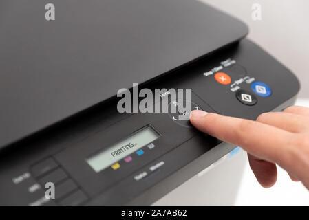 Hand pressing button on panel of printer. Multifunction device, printer, copier. Stock Photo