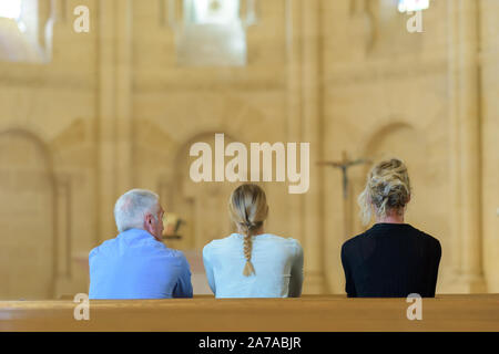 three people sat in church looking towards altar Stock Photo