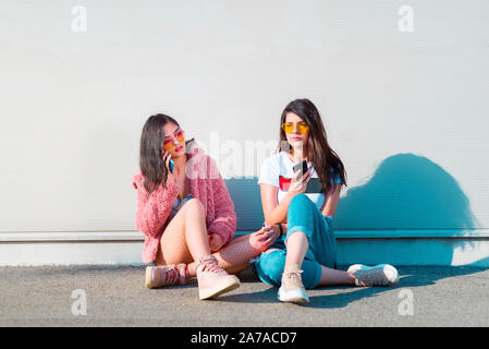 Two stylish young women using their mobile phones Stock Photo