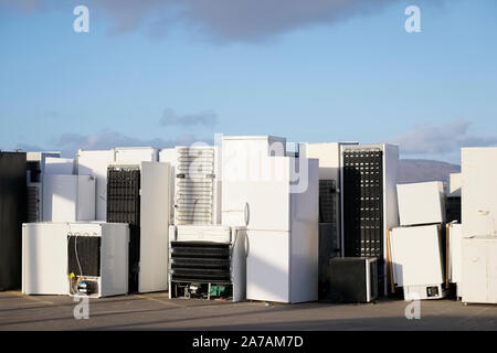 Old fridges freezers refrigerant gas at refuse dump skip recycle stacked pile plant help environment reduce pollution white silver Stock Photo