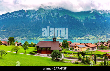 Panoramic view of swiss village Iseltwald with traditional wood church on the southern shore of Lake Brienz, Switzerland Stock Photo