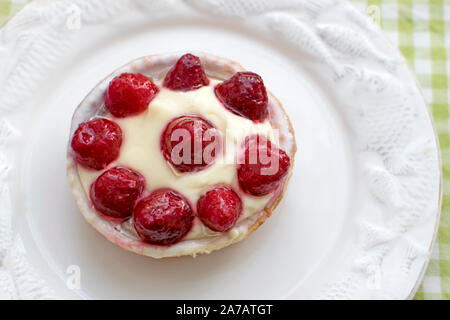 Cupcake with berries on a white round plate. Basket of shortcrust pastry with butter cream and strawberries. Sweet tasty pastries for tea. Desserts wi Stock Photo