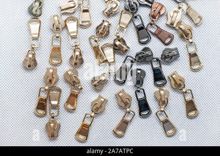Metal zipper for clothes, bags or shoes. Fittings for making wallets of gold and black color. zipper sliders on a white background. Stock Photo