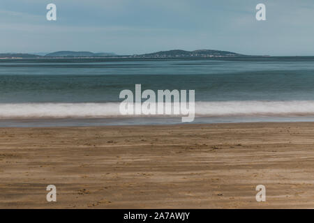 long exposure shot of pristine deserted Australian beach at dusk in Tasmania with moody tones and silky water effect and detail of coastline Stock Photo