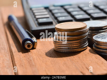 Coins and pens on calculators for calculating business concepts, coins and ballpen on table Stock Photo