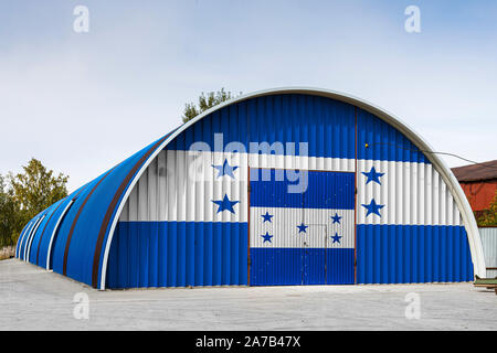 Close-up of the national flag of Honduras  painted on the metal wall of a large warehouse the closed territory against blue sky. The concept of storag Stock Photo
