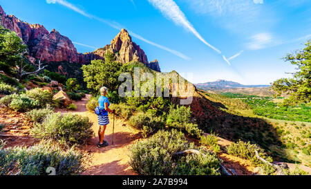 Woman hiker watching the sunrise over The Watchman peak in Zion National Park in Utah, USA, during an early morning hike on the Watchman Trail.