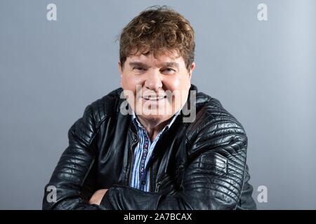 Dresden, Germany. 30th Oct, 2019. The singer Frank Schöbel sits in front of a photo wall in the boulevard theatre. The occasion is the presentation of the musical 'Frank Schöbel Story', which deals with the career of the GDR hit singer Frank Schöbel on stage. Credit: Sebastian Kahnert/dpa-Zentralbild/dpa/Alamy Live News Stock Photo