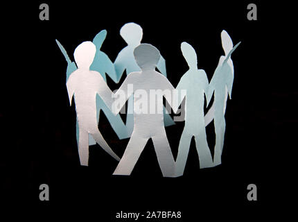 White paper cut into people hold their hands connected on black background
