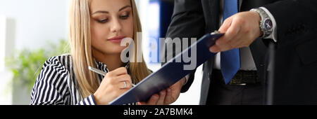 Beutiful thoughtful clerk signing important document Stock Photo