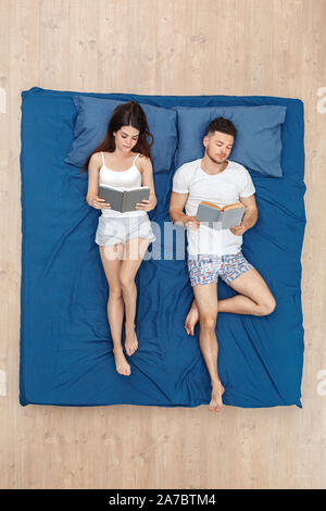 Young couple man and woman lying on bed top view reading books concentrated Stock Photo
