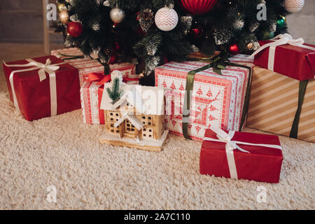 CLose-up of stack of festively wrapped gifts on the carpet under Christmas tree with Christmas balls. New Year is coming. Christmas concept. Stock Photo