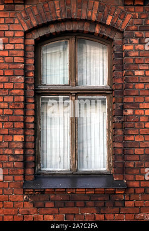 Tightly closed vintage vertical wooden window in red brick wall as fragment of old living house front view closeup Stock Photo