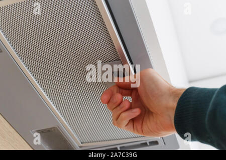 Man removing a filter from cooker hood for cleaning or service.. Close up Stock Photo
