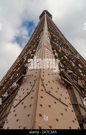 Low angle shot from the second level to the top of the Eiffel Tower in Paris. The portrait close-up view of the bronze painted metal framework reveals... Stock Photo