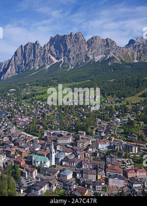 AERIAL VIEW. Upscale mountain resort with the lofty, craggy Monte Cristallo cliffs for background. Cortina d'Ampezzo, Dolomites, Veneto, Italy. Stock Photo