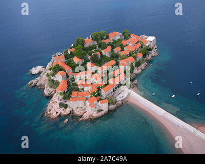 AERIAL VIEW. Five-star hotel built on a tied island, reachable by a sandy tombolo. Sveti Stefan, Montenegro. Stock Photo