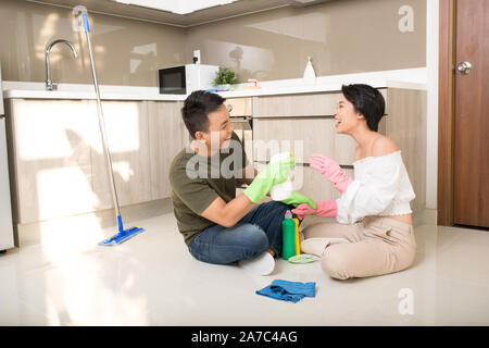 Young happy Asian couple is having fun while doing cleaning at home. Stock Photo