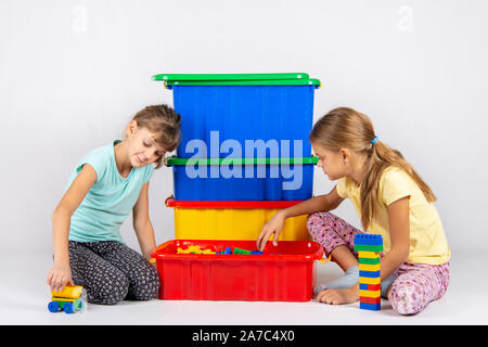 Two girls opened a box with a designer and start to play toys Stock Photo