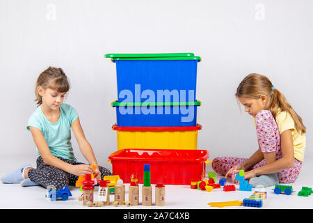 Two girls play toys, in the middle are boxes with toys Stock Photo