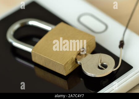 Padlock and key with fish hook on mobile phone - Concept of phishing and mobile security Stock Photo