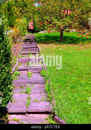 simple garden staircase made of reddish concrete slabs with blades of grass between the joints Stock Photo